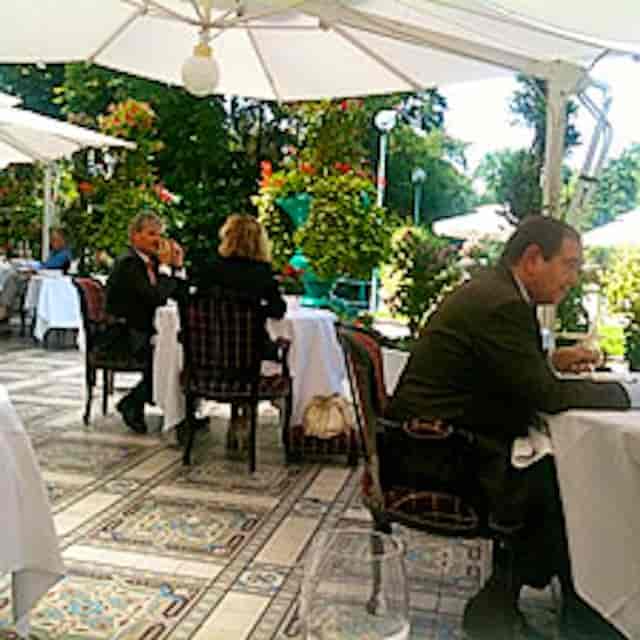 Elegant outdoor corporate luncheon setup at La Grande Cascade with umbrella-shaded dining tables.