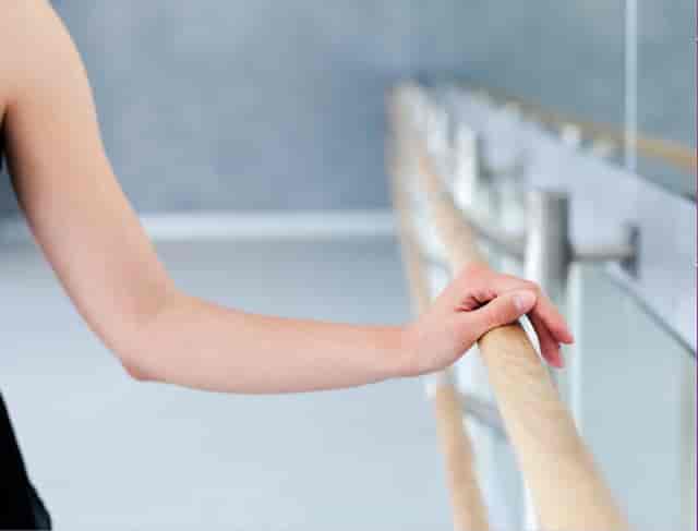 Dancer's hand on ballet barre at Unfurl Studios for performing arts events.
