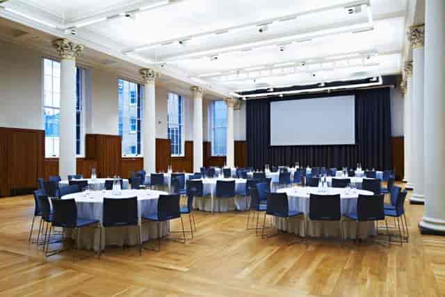 Great Hall at King's College London, set for a banquet or conference with elegant round tables.