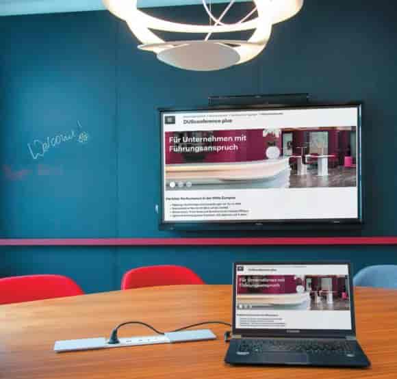 Modern DUSconference meeting room with dual-screen AV setup for hybrid corporate events.