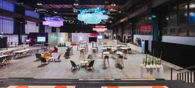Industrial-chic multi-purpose hall with lounge seating for corporate networking events.