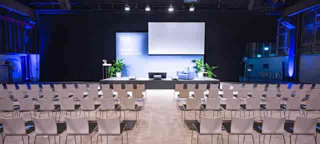 Professional fireside chat stage setup in a modern minimalist corporate event hall.