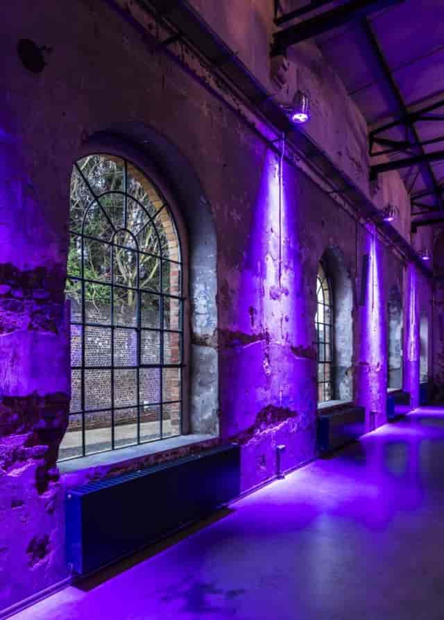 Industrial event venue with brick walls and vibrant uplighting for corporate parties or galas.