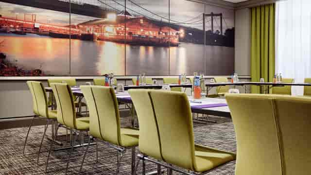U-shape meeting room in Cologne with lime-green chairs for corporate workshops and breakout sessions.