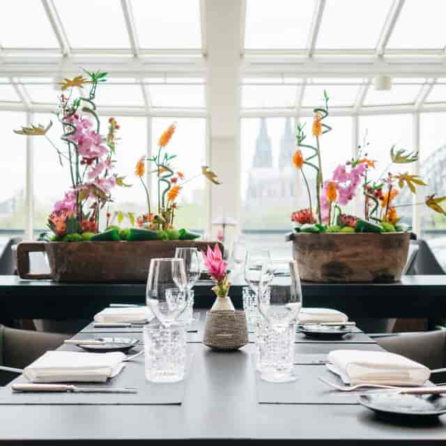 Upscale Glashaus Restaurant with floral decor and Cologne Cathedral view for corporate gala dinner.
