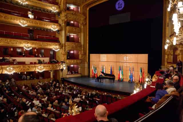 Plenary session in Sala Tenor Viñas, Gran Teatre del Liceu with stage branding and flags.