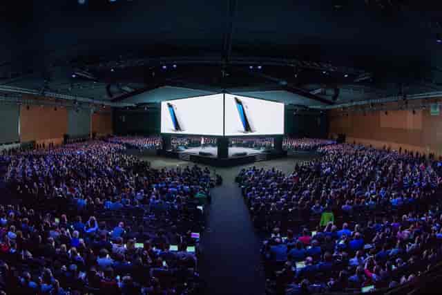 Auditori Fòrum CCIB concert hall with center-stage product launch and dual-screen AV setup.