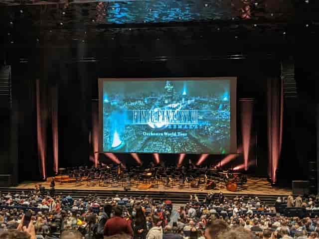 Concert hall stage with large projection screen for corporate event or orchestral performance.