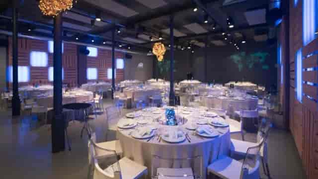 Industrial-chic event space with ghost chairs for corporate banquet and gala branding.