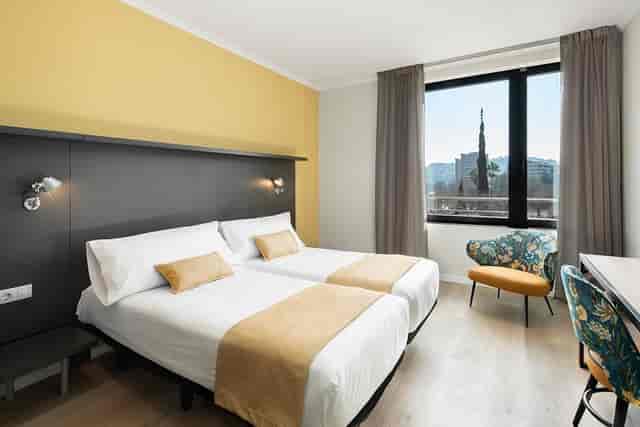 Twin guest room at Hotel Alimara with workspace, ideal for business event blocks and travel.