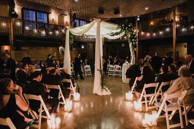 Industrial-chic wedding ceremony with floral chuppah at The Great Hall venue.