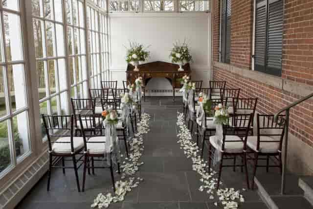 Elegant conservatory wedding ceremony setup with floral aisle markers at Langdon Hall.