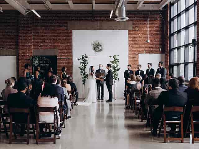 Minimalist industrial wedding ceremony with exposed brick and floor-to-ceiling windows.