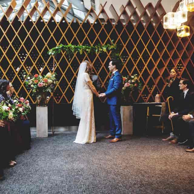 Intimate indoor wedding at Patio in Jump featuring a diamond-patterned architectural backdrop.