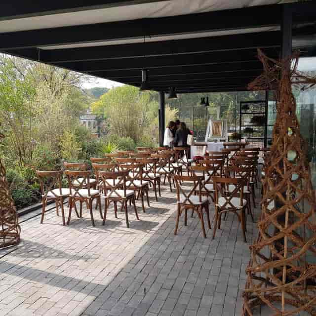 Upscale outdoor event at Cocina in Terraza Everest with rustic cross-back chairs and garden patio.
