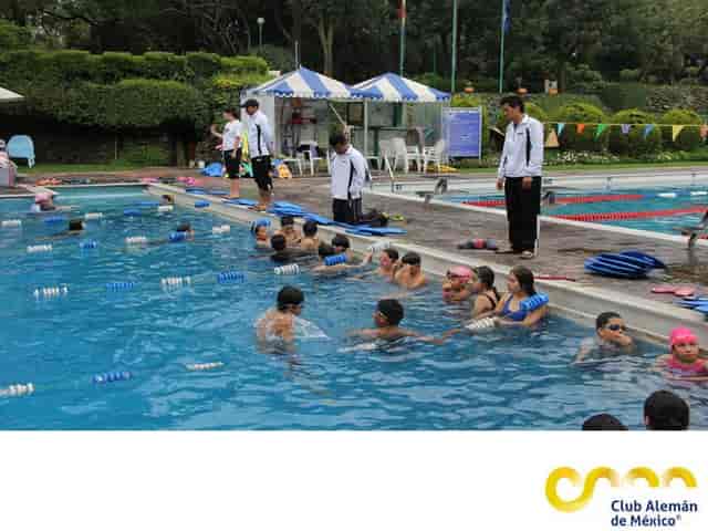 Outdoor team-building event at Club Alemán pool with branded staff and registration tent.