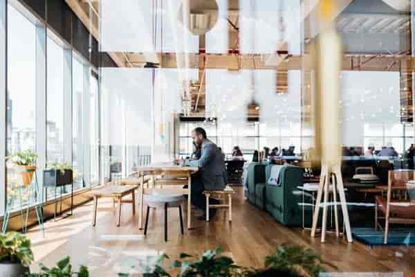 Modern WeWork dedicated desk in a light-filled open office for networking and breakout sessions.