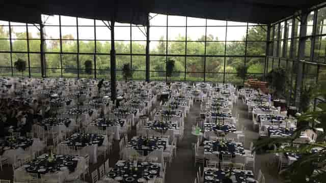 Glass-walled industrial banquet hall with crisp linens, perfect for corporate galas and weddings.
