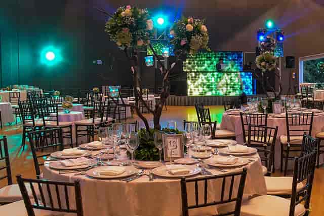 Ballroom event space with floral centerpieces and stage lighting for corporate gala or wedding.