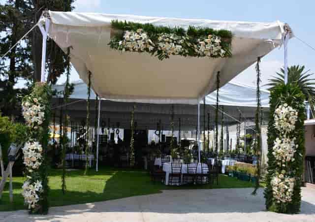 Tented event lounge at Salón y Jardín Los Pinos with elegant floral installations for weddings.