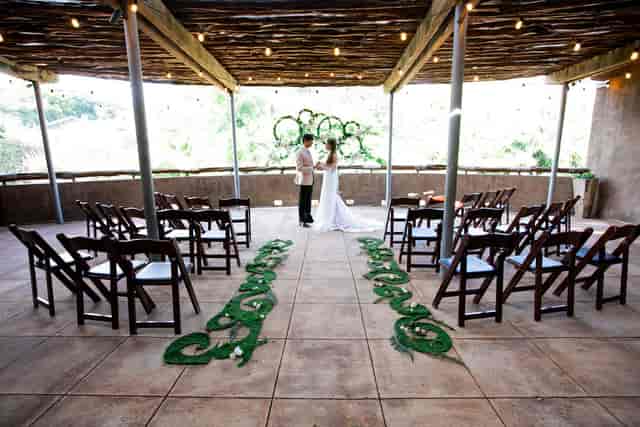 Rustic outdoor wedding ceremony at San Antonio Zoo Hippo Overlook with bistro-lit pergola.
