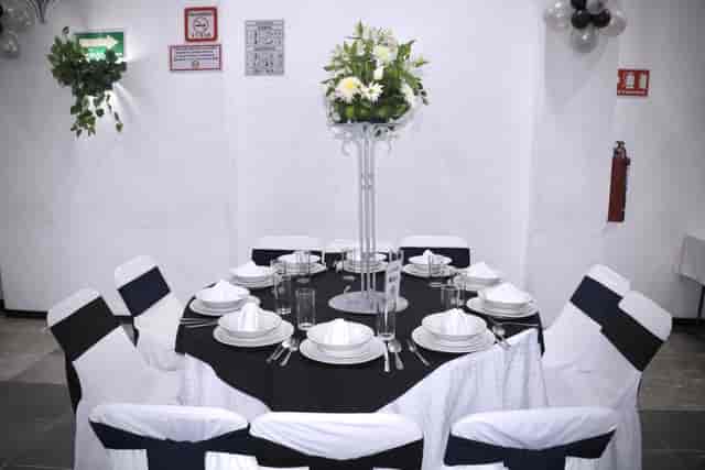 Salones Amarilis convention center event setup with monochromatic decor and floral centerpiece.