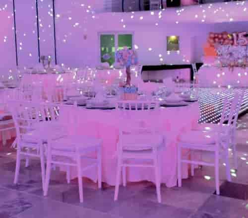 Purple-lit ballroom with Chiavari chairs and dance floor for Quinceañera or formal celebration.