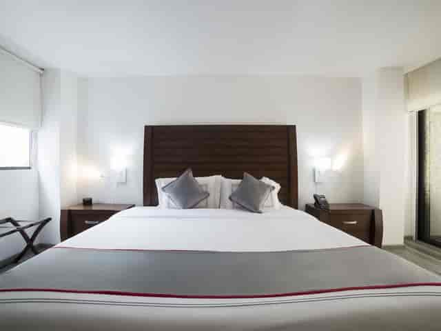 Hotel room at Suites Arboleda 215, minimalist design for business travel and conference lodging.
