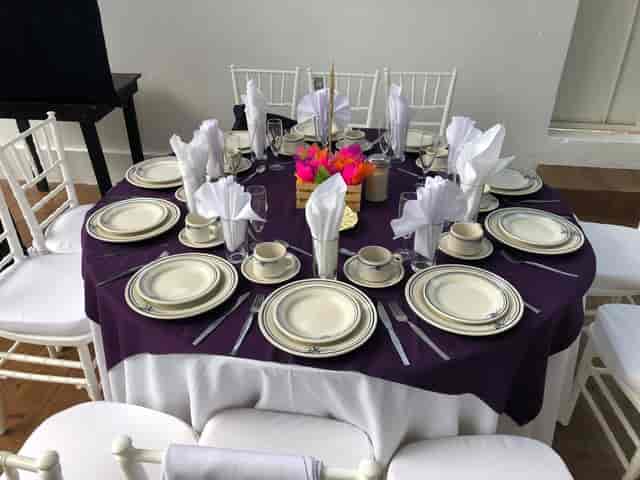 Function room with purple banquet setup, floral centerpieces, and Chiavari chairs for events.