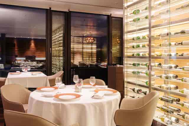 Upscale private dining room with illuminated wine cellar for corporate events and VIP dinners.