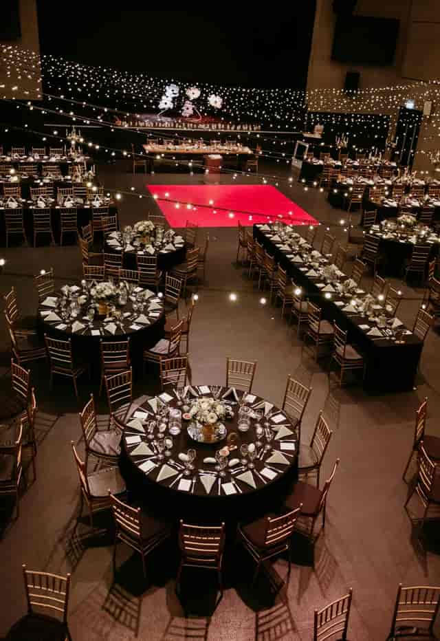 Black and gold gala setup with red dance floor for corporate events and formal banquets.
