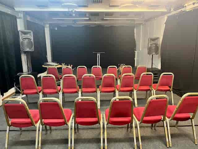 Premier Room 1 setup with red chairs for a seminar, featuring audio equipment and clean backdrop.
