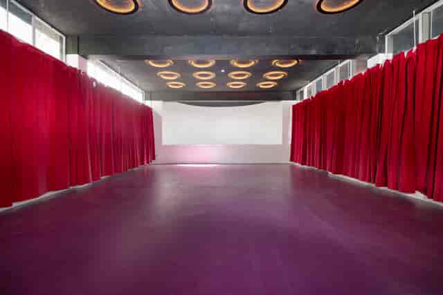 Versatile event space with red curtains, ideal for conferences and social gatherings.