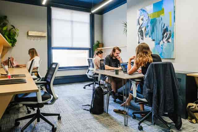 Coworking space with ergonomic workstations and kitchen for productive team breakout events.
