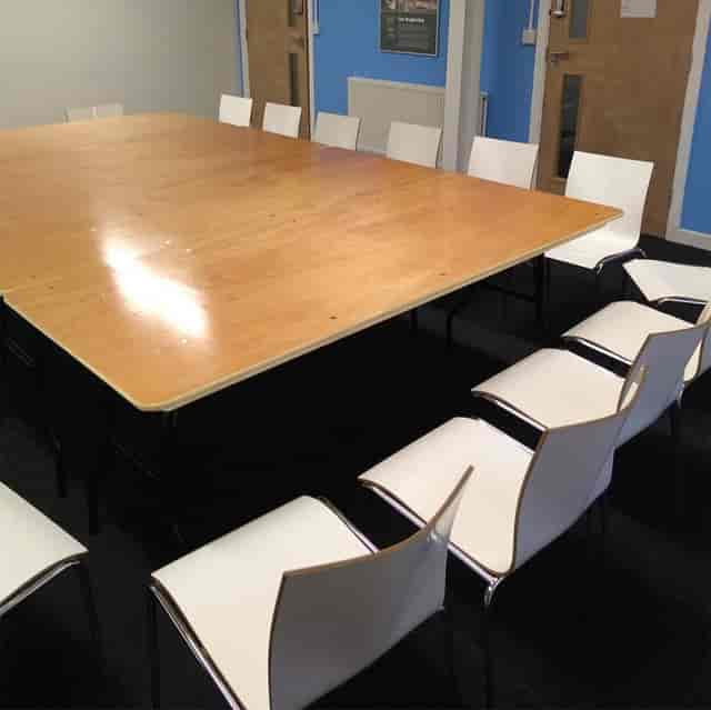 Boardroom at Spaces@321 with wooden tables and mismatched chairs for corporate meetings.
