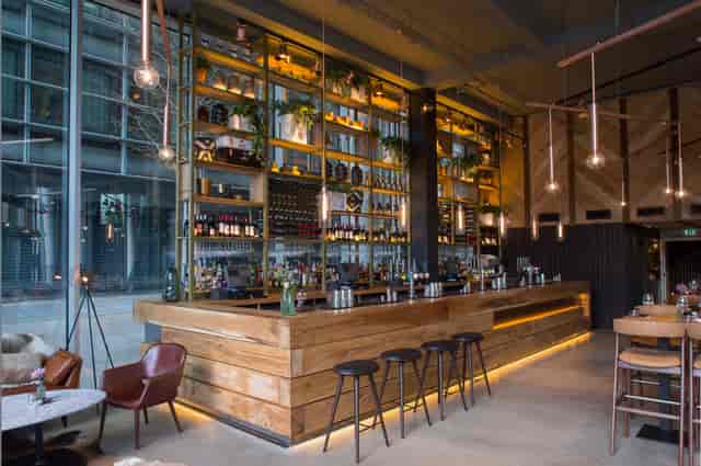 Modern bar with wooden counter in The Refinery, ideal for networking events and gatherings.
