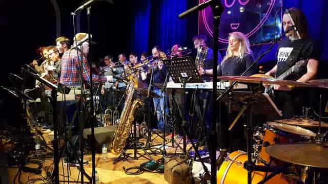 Band on the Wall education center with large ensemble on stage for live music event production.