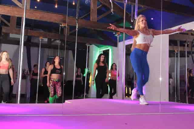 Nutritionist leading fitness event in high-energy studio with mirrored walls and stage lighting.