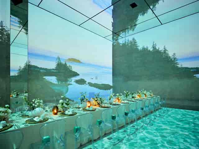 Event space with long dining table and nature projections for upscale gatherings.