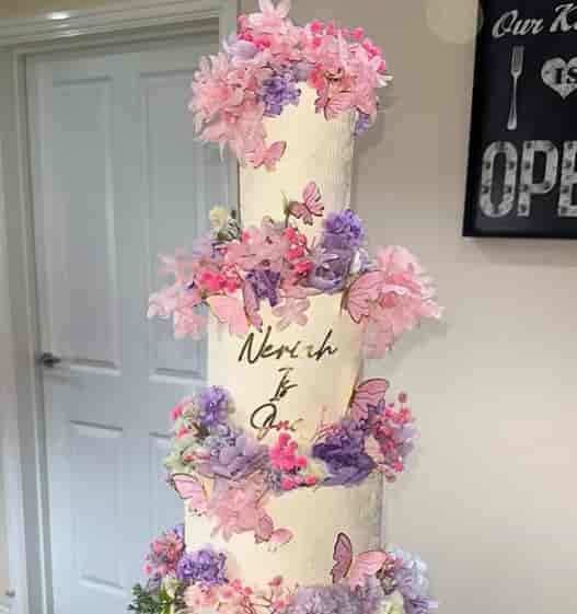 Multi-tiered wedding cake with floral and butterfly accents in a luxury London kitchen studio.