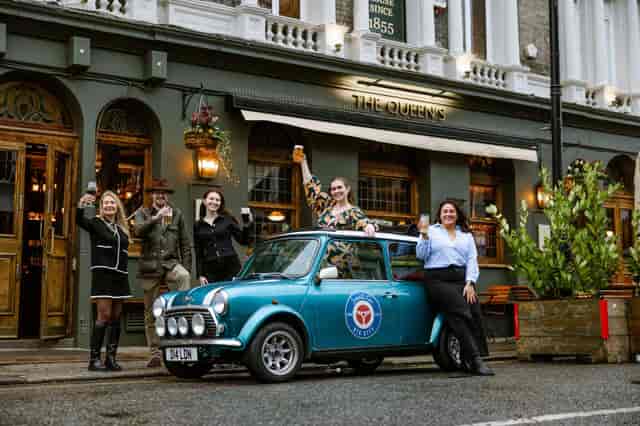 Vibrant Queen's Quarters pub scene with vintage car for themed event promotions.