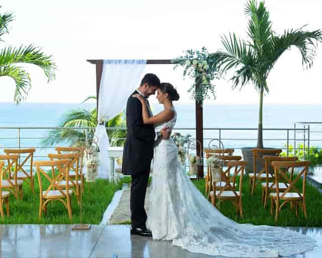 Oceanfront Beach Club wedding setup with floral arch and ocean backdrop.