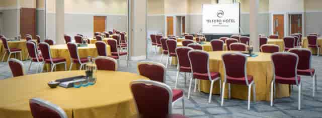 Meeting room at The Vermont Hotel with round tables, perfect for corporate events.