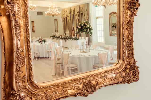 Wedding reception in Kennedy Suite, Doxford Hall: elegant table decor and ornate gold mirror.