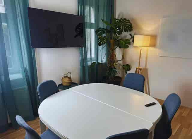 Modern seminar room with round table, natural light, ideal for collaborative meetings.