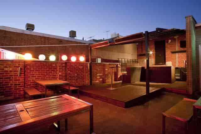 Industrial-chic outdoor venue with stage and string lighting for networking events and mixers.