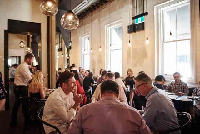 Corporate networking event in a high-ceilinged venue with natural light.