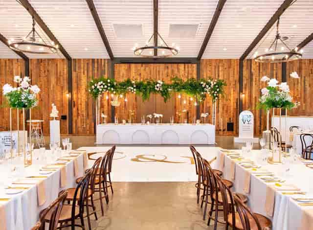 Rustic-chic Sandalera Room wedding venue with custom dance floor and floral head table.