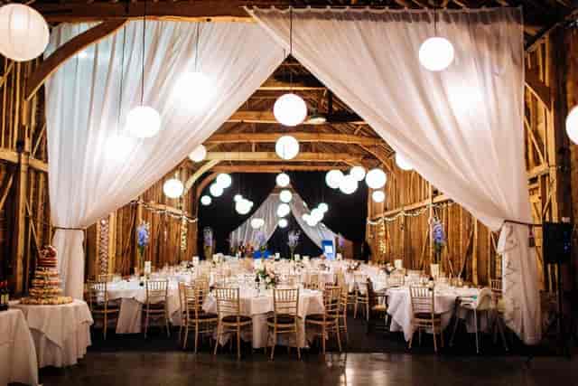 The Long Barn Childerley Hall with elegant draping and pendant lights for rustic wedding venues.