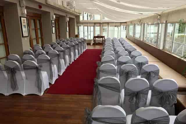 Elegant event space with covered chairs and natural light, perfect for weddings and formal gatherings.